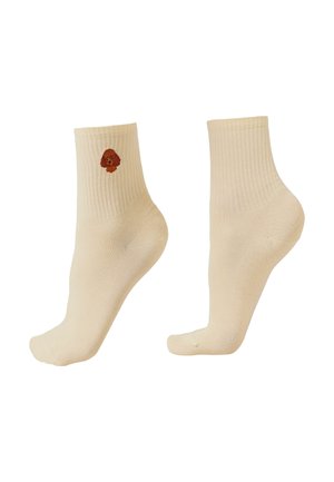 Béžové kotníkové ponožky s žebrovanými lemy, jedna ponožka má na vnější straně malý vyšívaný hnědý obličej psa.