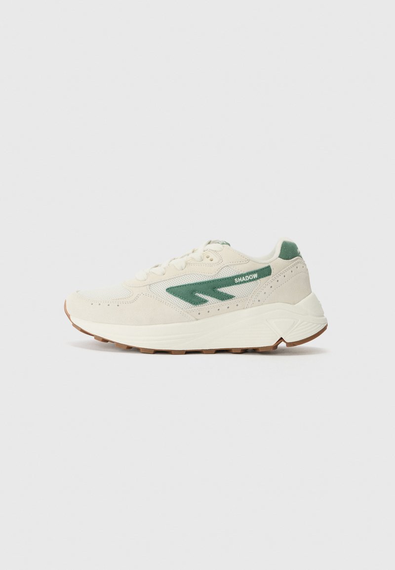 White athletic shoes with green accents, mesh and suede materials, rounded toe, padded collar, and textured rubber sole.