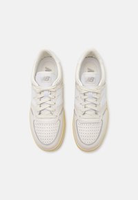 Weiße Ledersneaker mit perforierter Zehenpartie, hellgrauen Akzenten, gepolstertem Zungenbereich und cremefarbener Gummisohle. Schnürsenkel in passender Farbe.