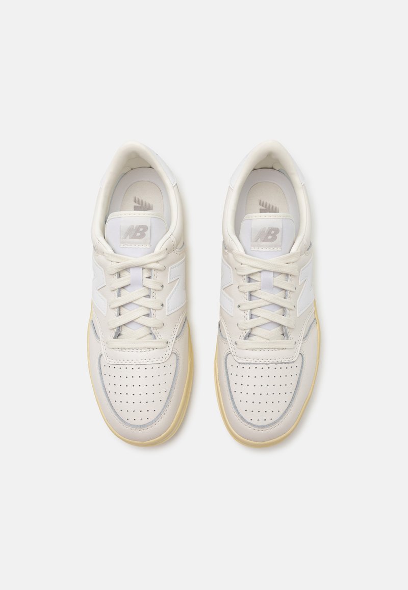 Weiße Ledersneaker mit perforierter Zehenpartie, hellgrauen Akzenten, gepolstertem Zungenbereich und cremefarbener Gummisohle. Schnürsenkel in passender Farbe.