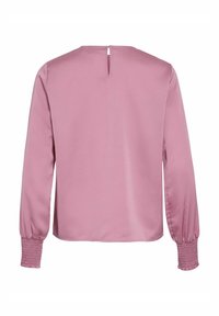 Blouse rose à manches longues avec une ouverture en forme de trou de serrure dans le dos. Tissu lisse et poignets froncés ajoutent de la texture et du détail au design simple.