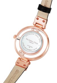 Reloj de pulsera redondo con caja de acero inoxidable oro rosa, esfera transparente, correa de cuero negro y un dial minimalista blanco.