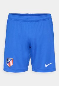 Blå træningsshorts med elastisk talje, der har et holdlogo på venstre side og en hvid Nike swoosh på højre side.