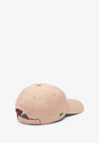 Casquette de baseball en coton rose clair, avec une visière courbée et une sangle arrière ajustable. Présente un petit logo brodé vert sur le côté.