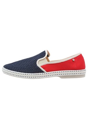 Chaussure slip-on avec une avant en maille marine, un arrière en tissu rouge, des garnitures blanches, et une semelle blanche avec un motif de points noirs.