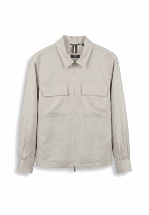 Veste chemise beige clair à manches longues avec fermeture éclair, col et deux poches avant à rabat, présentée à plat sur fond blanc.