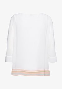Vit blus med trekvartsärmar, med upprullade manschetter och en nederkant med randig design i kräm, rosa och blå. Slät textur.