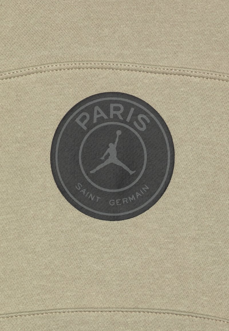 Felpa beige con un logo circolare nero contenente il testo "PARIS" e "SAINT GERMAIN" e un design di una figura in salto al centro.