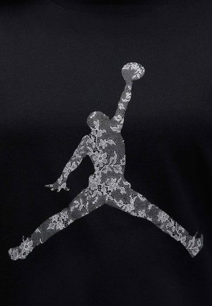 Schwarzes T-Shirt mit einem weißen, Spitzenmuster-Jumpman-Logo. Das Design zeigt komplizierte florale Details innerhalb des Logos.