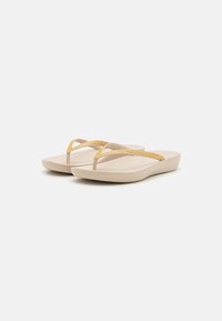 Beige flip-flops med gule teksturerte stropper, flat design, polstret såle og avrundede kanter. Passer til hverdagsbruk.