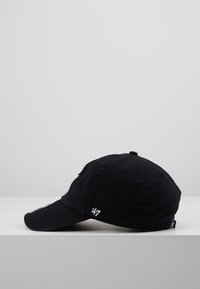 Black cotton cap with a curved visor, featuring white embroidered "47" on the side and contrasting logo on the front; textured fabric.