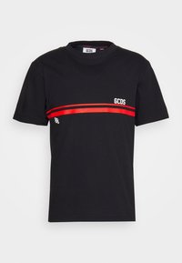 Camiseta de algodón negra con cuello redondo, que presenta una franja roja horizontal y el logo blanco "GCDS" en el frente. Mangas cortas, ajuste estándar.