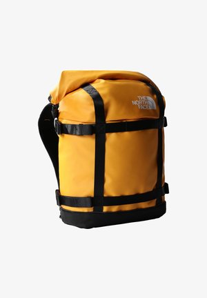 Gele waterdichte stoffen rugzak met zwarte riemen, oprolbare sluiting en The North Face-logo. Gestructureerd lichaam met meerdere externe riemen.