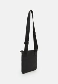 Black textured crossbody bag with a flat rectangular shape, featuring an adjustable strap and a zipper closure on top.