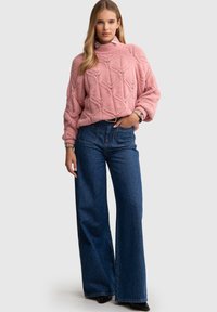 Roosa kudumistega sviiter, millel on tekstuuriga rombimuster, kõrge kaelus ja laiad varrukad, kombineeritud kõrge vöökohaga siniste denimist heleroheline teksadega.