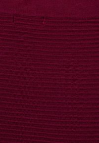 Bordeaux gekreukt stof met horizontale ribbelpatronen. Het materiaal lijkt zacht en rekbaar, geschikt voor aansluitende kleding.