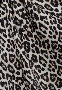 Leopardenmuster-Stoff mit beigem Hintergrund und kräftigen schwarzen Flecken, die unterschiedliche Formen und Texturen im gesamten Design zeigen.