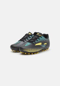 Botas de fútbol negras con patrones abstractos en amarillo y turquesa, parte superior sintética texturizada y tacos amarillos en la suela para tracción.