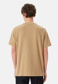 T-shirt khaki a maniche corte con un motivo testurizzato, scollo a girocollo e orlo dritto. Visibile da dietro, con una vestibilità comoda.