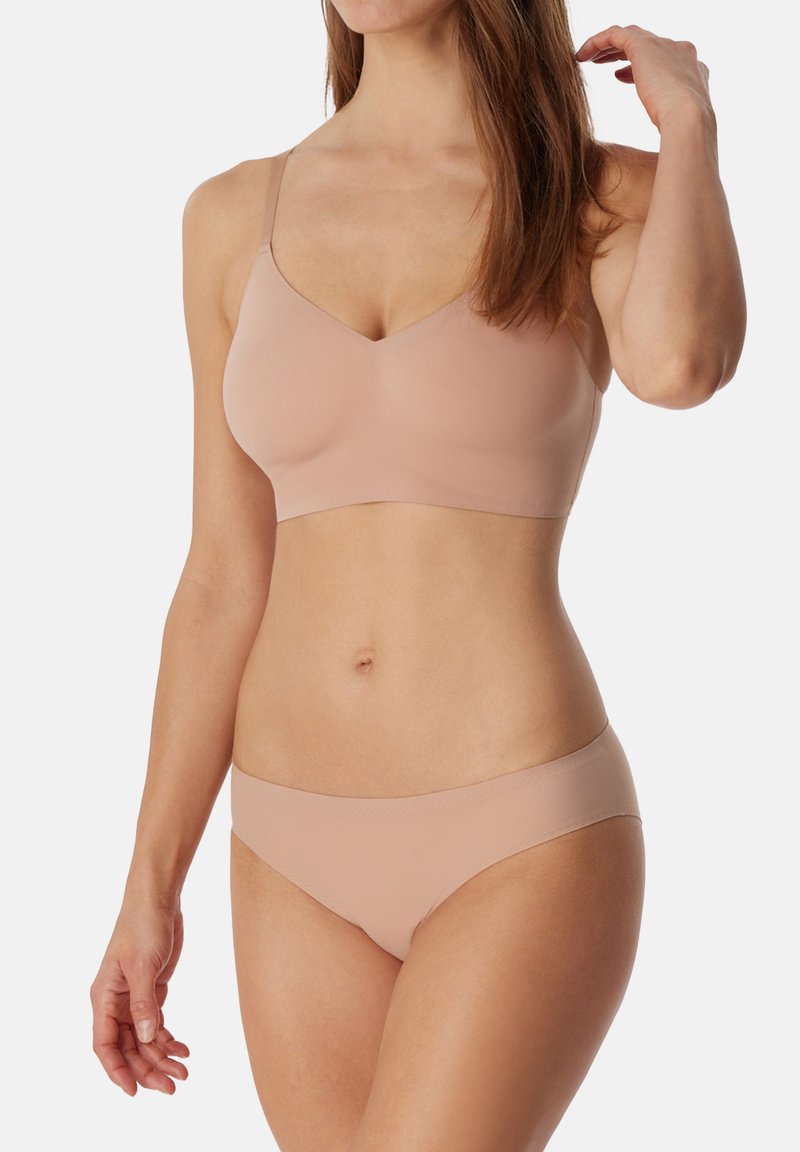 Sømløs nude bh med justerbare stropper og V-hals design, parret med matchende bikiniundertøj. Glat, strækbart stof.