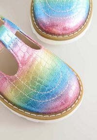 Children's shoes with a shiny, gradient finish in pink, blue, and green; reptile-like texture; white sole; stitched detailing.
