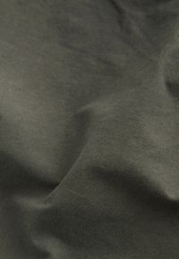 Olive zöld szövet, sima textúrával, finom gyűrődésekkel és matt felülettel. Az anyag könnyűnek és légáteresztőnek tűnik.