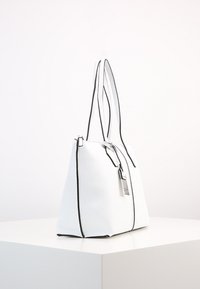 Witte kunstlederen totebag met zwarte accenten, hoge vorm, dubbele handvatten en een zilveren labelaccent. Voorzien van een rits bovenaan.