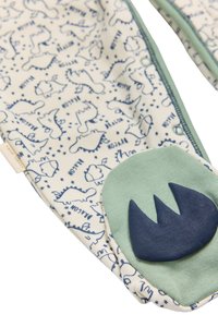 Tela de algodón con un fondo crema que presenta ilustraciones de dinosaurios azules y estrellas. Acentos en suave verde y azul marino en el borde inferior.