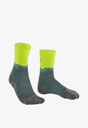 Calcetines de montaña en verde y amarillo con una base gris. La parte superior es de un amarillo brillante, que se transforma en verde oscuro y gris.