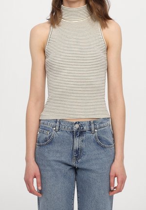 Haut sans manches rayé avec un col montant en crème et noir. Associé à un jean en denim bleu taille haute, présentant un design classique à cinq poches.