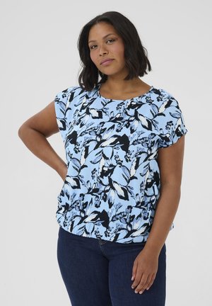 Blouse bleu clair à manches courtes avec un imprimé floral noir et blanc. Tissu doux avec une coupe ample et un col rond.