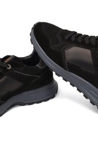 Sneaker in suede nero con suole in gomma, caratterizzati da un pannello nero liscio, dettagli testurizzati e una suola grigia a contrasto con lacci.