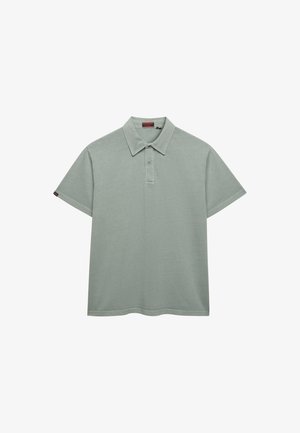 Polo à manches courtes vert clair avec col, patte de boutonnage à deux boutons et petite étiquette logo sur la manche gauche.