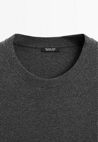 Pull gris foncé à col rond avec une étiquette visible indiquant Massimo Dutti fabriqué au Portugal sur l'encolure intérieure.