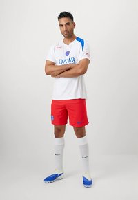 Witte trui met blauwe accenten en "Qatar" logo, rode broek met blauwe details, witte sokken en blauwe voetbalschoenen.