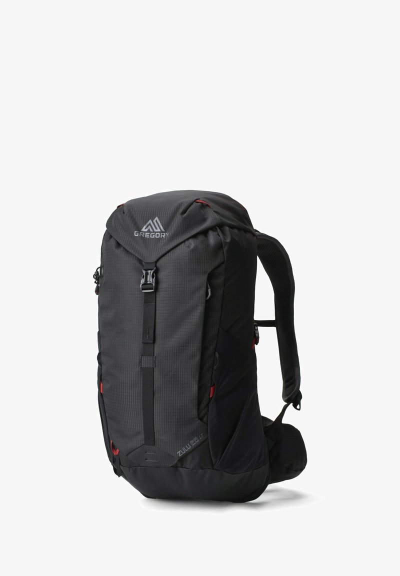 Sac à dos noir avec une finition texturée, bretelles ajustables, boucles à l'avant et accents rouges. Comprend un compartiment spacieux et des poches latérales.