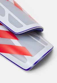 Siliconen flipcover in doorzichtig, met rode diagonale strepen en een stippenstructuur. Afgeronde randen, flexibele vormgeving en een levendig kleurcontrast.