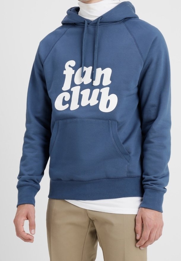 Mörkblå hoodie med framficka, vit text "fan club" och luva med dragsko; tillverkad av mjukt, texturerat tyg.