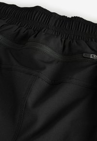 Black shorts featuring an elastic waistband and a zippered back pocket, made from smooth fabric with reinforced seams and simple design.