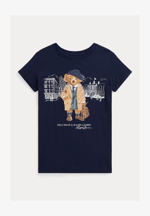 Navy Baumwoll-T-Shirt mit einem Grafikdesign eines bekleideten Bären, der einen Mantel, einen Hut und eine Tasche trägt, vor einem Stadtbild.