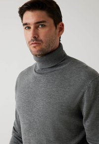 Harmaa turtleneck-neule, joka on valmistettu pehmeästä neulekankaasta. Ominaisuuksiin kuuluu korkea kaulus, muotoiltu malli ja ribbimäinen kaulus. Sujuva pinta ja minimaalinen yksityiskohtaisuus.