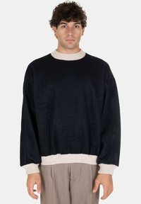 Maglione blu navy con colletto e polsini a costine crema; vestibilità rilassata e tessuto testurizzato; maniche lunghe; design semplice senza fantasie.