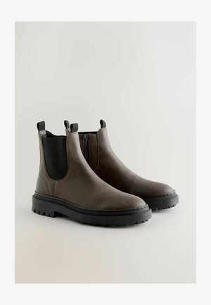 Barna bőr Chelsea csizmák elasztikus oldalsó panelek, húzófülek és masszív fekete gumitalp jellemzik, sima felülettel és minimális varrással.