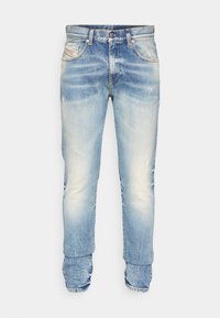 Vaaleansiniset farkut, joissa haalistettu pesu, viiden taskun malli, napillinen kiinnitys ja hieman kapeammat lahkeet. Reisien kohdalla kulutettuja yksityiskohtia.