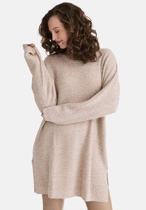 Gestrickter Oversized-Pullover in hellem Beige, mit strukturiertem Ripp-Design, langen Ärmeln und seitlichen Schlitzen für Bewegungsfreiheit.