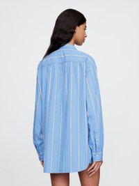 Lys blå oversized skjorte med vertikale hvite striper, knappe-ermer og detaljer med bakfold. Mykt stoff med en avslappet silhuett.
