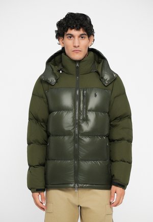 Olijfgroene pufferjack met een glanzend borstpaneel, ritssluiting, hoge kraag en afneembare capuchon, met een logo aan de linkerkant.