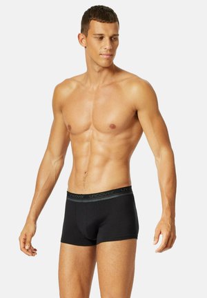 Boxer di colore nero con una morbida fascia elastica in vita che presenta il marchio "uncover", design aderente e materiale in cotone liscio.