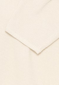 Tissu en tricot côtelé de couleur crème, plié pour montrer la texture et les détails de la couture.
