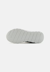 Semelle de chaussure avec une surface en caoutchouc blanc texturé ; présente de multiples rainures et crêtes pour une meilleure adhérence et traction.
